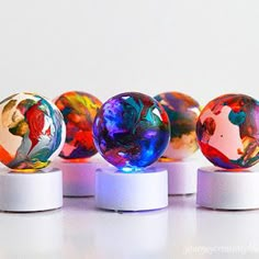 four different colored marbles sitting on top of each other in front of a white background