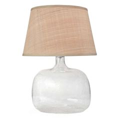 a clear glass table lamp with a beige shade on the base and a light brown linen lampshade