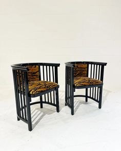 a pair of black chairs with tiger print upholstered backrests, side by side