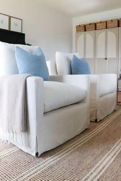 a living room with white furniture and blue pillows