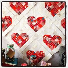 a quilted heart wall hanging on the wall next to some jars and other items