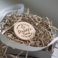 a wooden tag that says daddy's turn is in a box with some shredded up wood