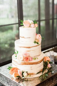 a three tiered cake with flowers on top is sitting on a silver platter