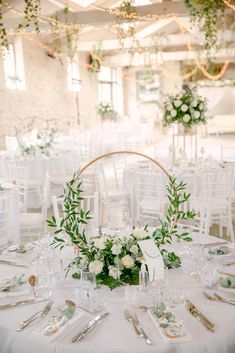 a table set up with white flowers and greenery