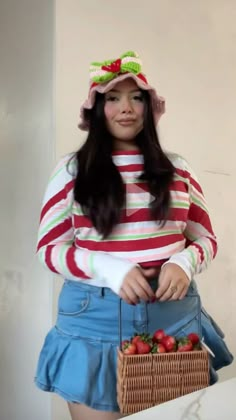 a woman holding a basket with strawberries in it and wearing a striped shirt over her top