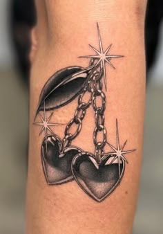 a tattoo on the leg of a woman with two hearts and a chain attached to it