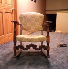 an old rocking chair sitting on the floor in front of a wooden paneled door