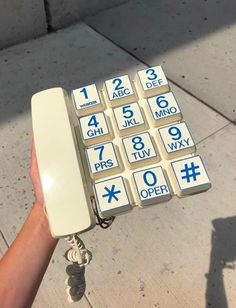 a hand holding a phone with numbers on it and keys attached to the back end