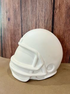 a white football helmet on top of a wooden table next to a wood plank wall