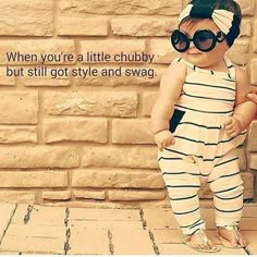 a baby wearing sunglasses standing next to a brick wall with the words when you're a little chubby, but still got style and swag