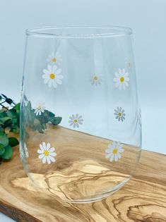 a glass sitting on top of a wooden cutting board next to a flower pot and plant