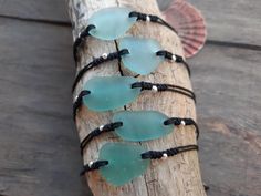 four pieces of sea glass sitting on top of a piece of driftwood