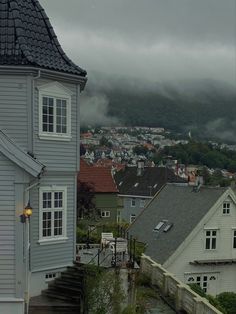 a view of some houses and mountains in the distance, with rain coming down on them