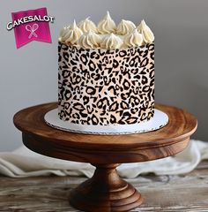 a leopard print cake with white frosting on a wooden stand