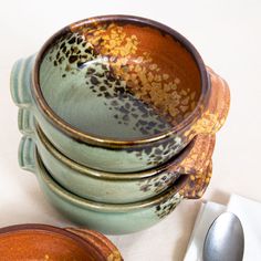 a stack of four bowls sitting on top of a table next to a fork and spoon