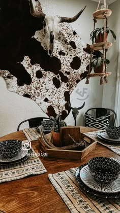 the table is set with black and white plates, silverware, and a cow's head