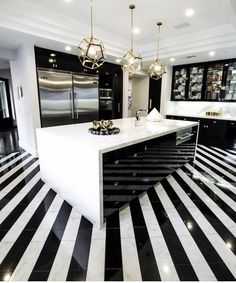 a kitchen with black and white stripes on the floor, gold lights hanging from the ceiling