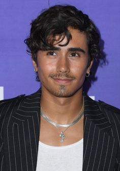 a close up of a person wearing a suit jacket and silver choker on his neck