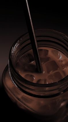 a glass jar filled with liquid and a black straw sticking out of it's top