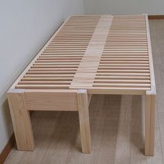 a wooden bed frame sitting on top of a hard wood floor next to a white wall