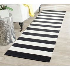 a black and white striped rug is on the floor next to a table with a vase