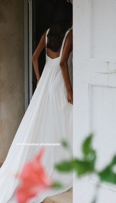 a woman in a long white dress is standing by the door and looking at her reflection