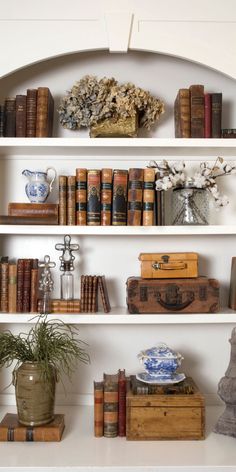 a white shelf filled with lots of books and vases on top of it's shelves