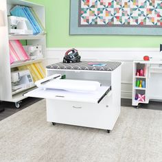 a sewing machine sitting on top of a white table next to a shelf filled with craft supplies