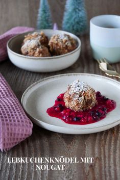 a white plate topped with food next to two bowls filled with blueberries and powdered sugar