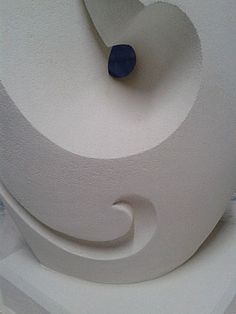 a white sculpture with a blue object in the middle of it's center piece