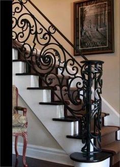 a stair case with wrought iron handrails in a living room next to a painting on the wall