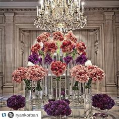 a bunch of flowers that are in vases on a table with a chandelier