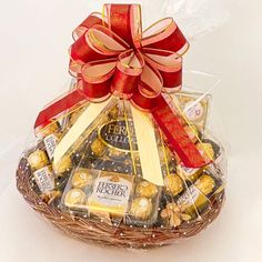 a basket filled with lots of chocolates and nuts in red ribbon tied around it