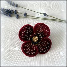 a flower brooch sitting on top of a white table next to lavenders and flowers