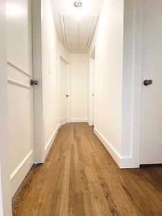 an empty hallway with wooden floors and white walls