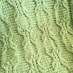 a close up view of a blanket made with green knitted material and crochet