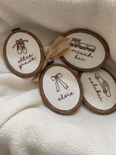 four embroidered wooden coasters with handwritten words on them, tied to a ribbon