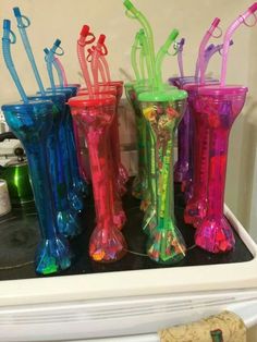 four different colored glass vases sitting on top of a white stovetop next to a corkscrew