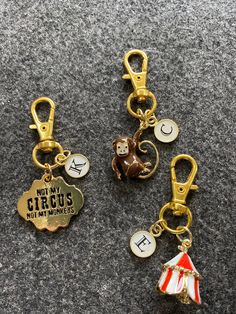 three key chains with charms on them sitting on the ground next to eachother