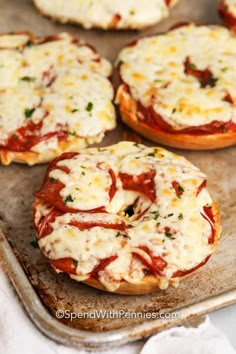 several small pizzas are on a baking sheet