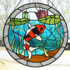 a stained glass window with a fish in the water and leaves on it's side