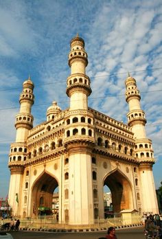 a large white building with two towers in front of blue sky and clouds behind it