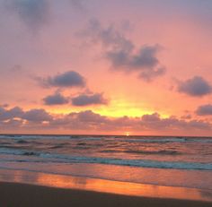 the sun is setting over the ocean with clouds in the sky and waves on the beach