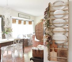 a room filled with lots of white plates and wooden shelves next to a dining table