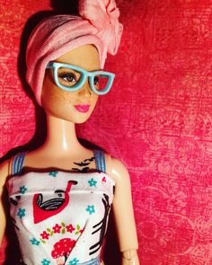 a barbie doll wearing sunglasses and a pink towel on top of it's head