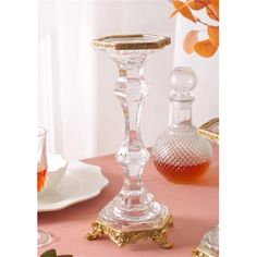 a glass candle holder sitting on top of a table next to a plate and cup