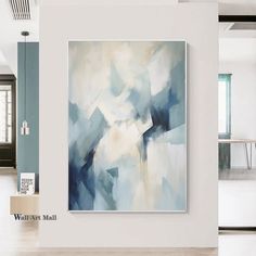 an abstract painting hangs on the wall in a white room with blue and beige accents