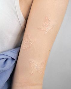 a woman's arm with two white butterflies painted on the back of her arm