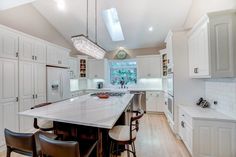 a large kitchen with white cabinets and an island