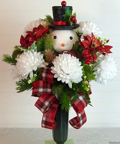 a snowman is sitting in a vase with flowers